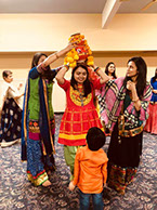 Members at Fresno County Gujarati Samaj help a young girl with her head dress.
